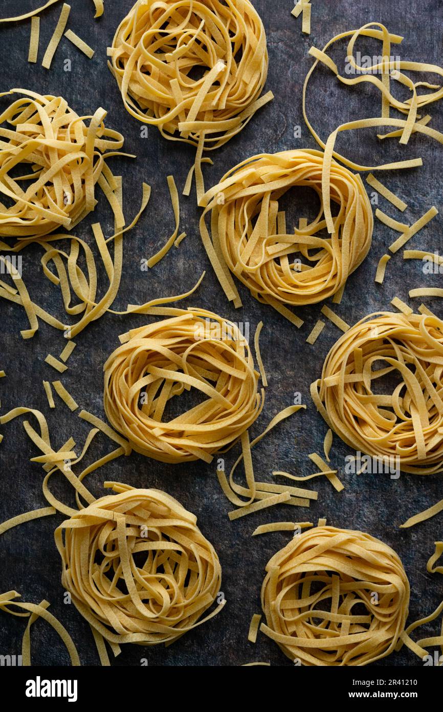 Tagliatelle nids de pâtes entourés de nouilles cassées éparses : plusieurs  nids de pâtes séchées de nouilles placées sur un comptoir de cuisine Photo  Stock - Alamy