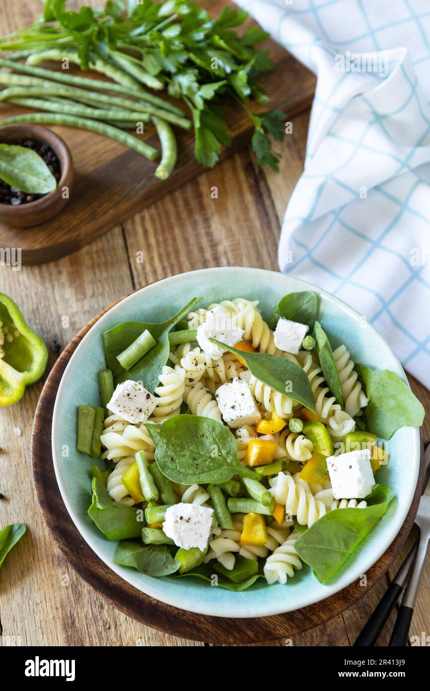 Salade de pâtes fraîches et délicieuses, cuisine italienne. Pâtes fusilli de blé entier avec féta, haricots verts et poivre sur fond de bois. Banque D'Images