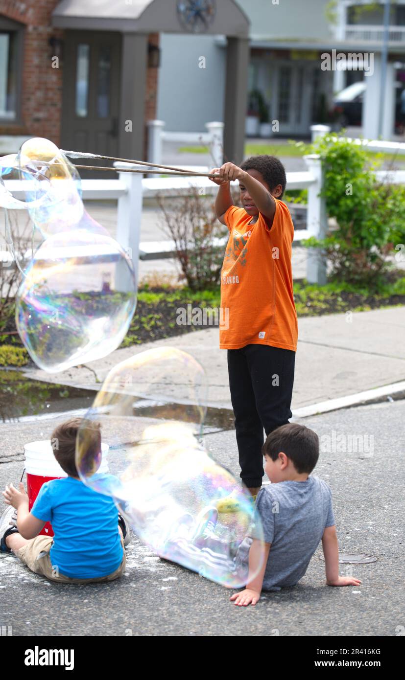 Rues ouvertes - Hyannis, Massachusetts, États-Unis. Un jeune garçon qui fait des bulles sur main Street. Banque D'Images