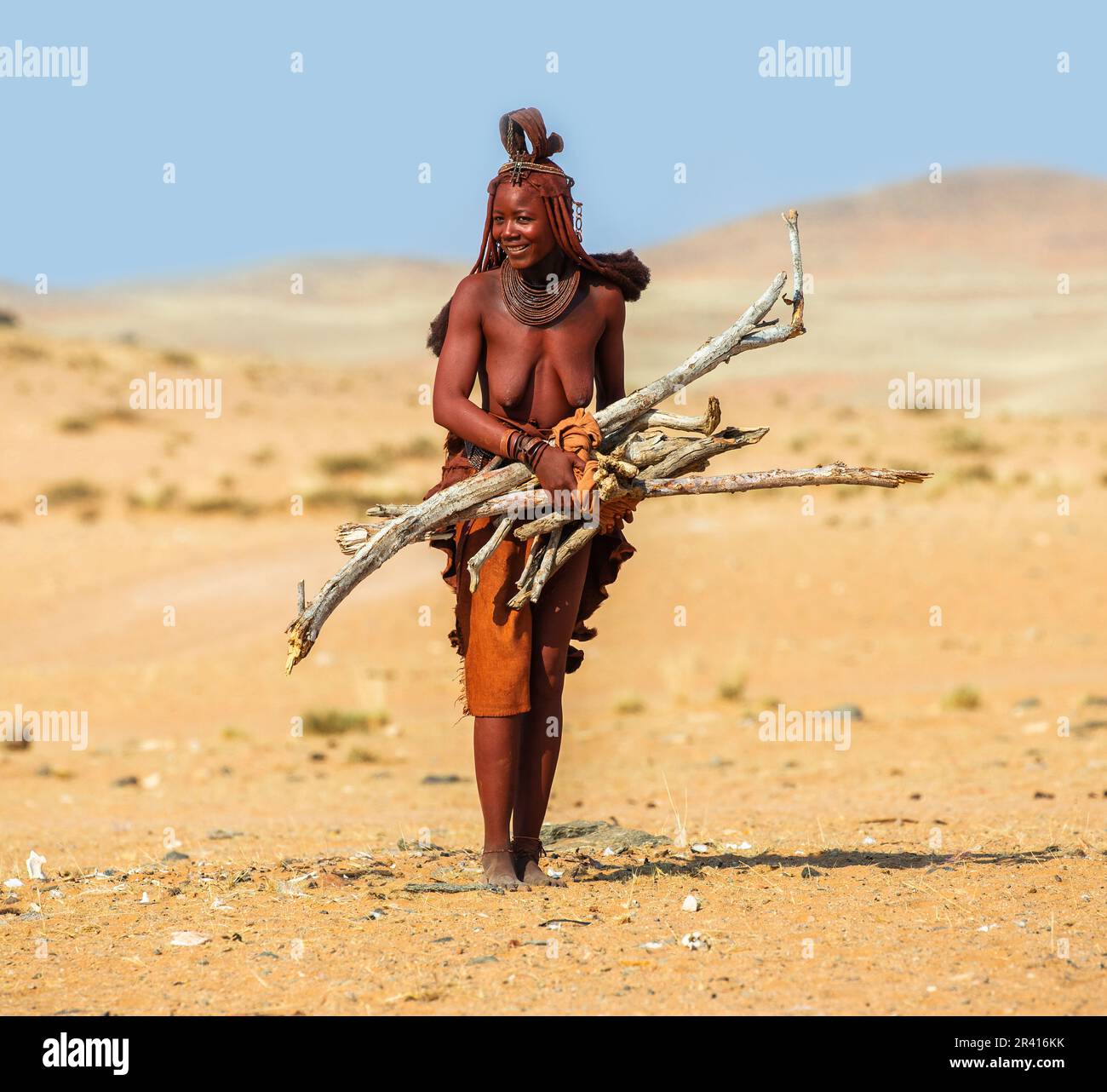 La femme Himba marche avec du bois de chauffage dans le désert. Banque D'Images