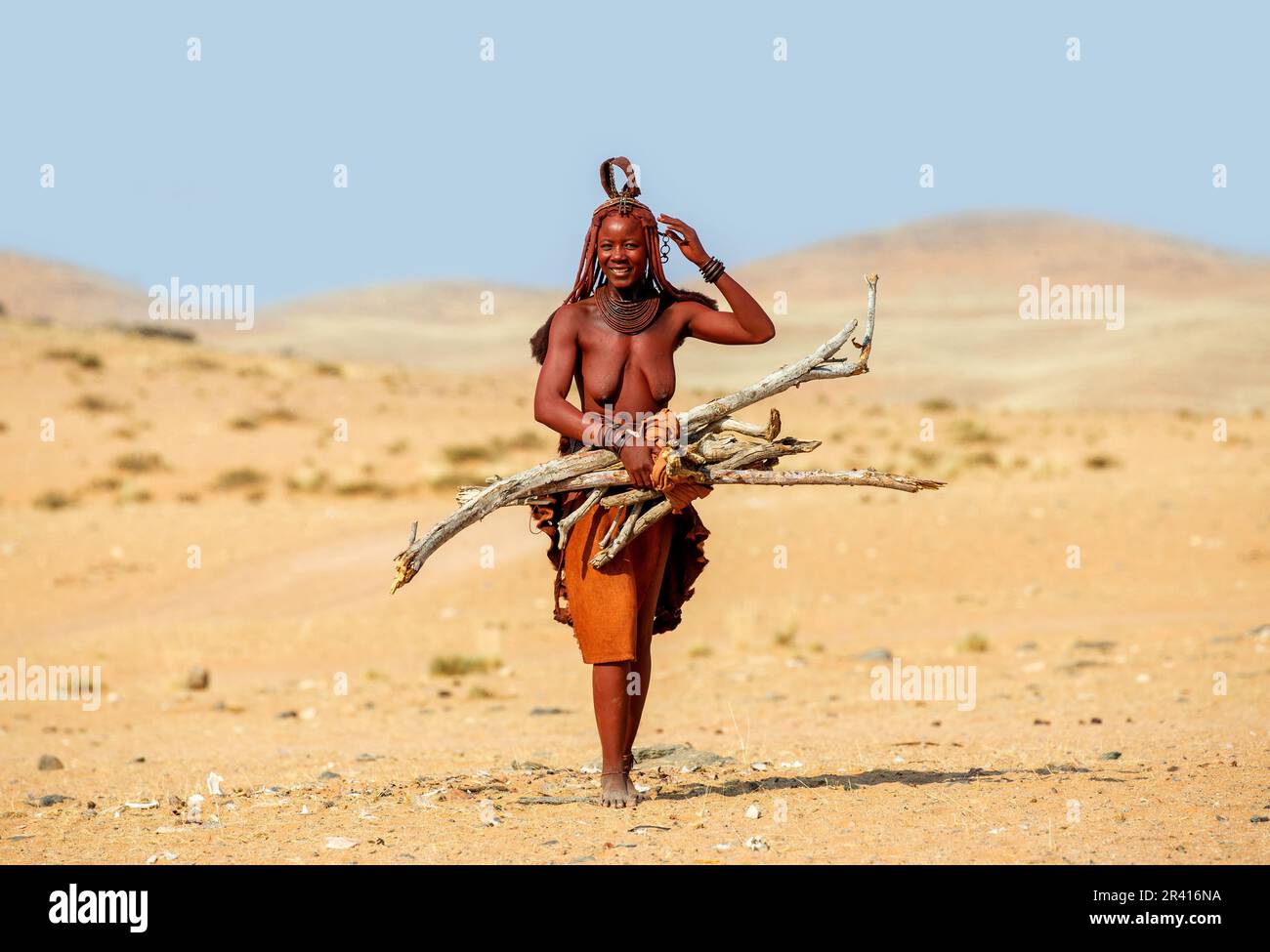 La femme Himba marche avec du bois de chauffage dans le désert. Banque D'Images