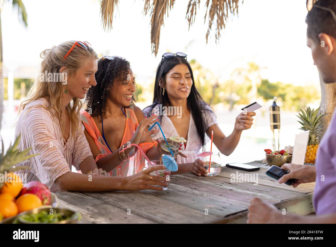 Des amis heureux et variés qui font la fête à la plage et achètent des cocktails au bar Banque D'Images