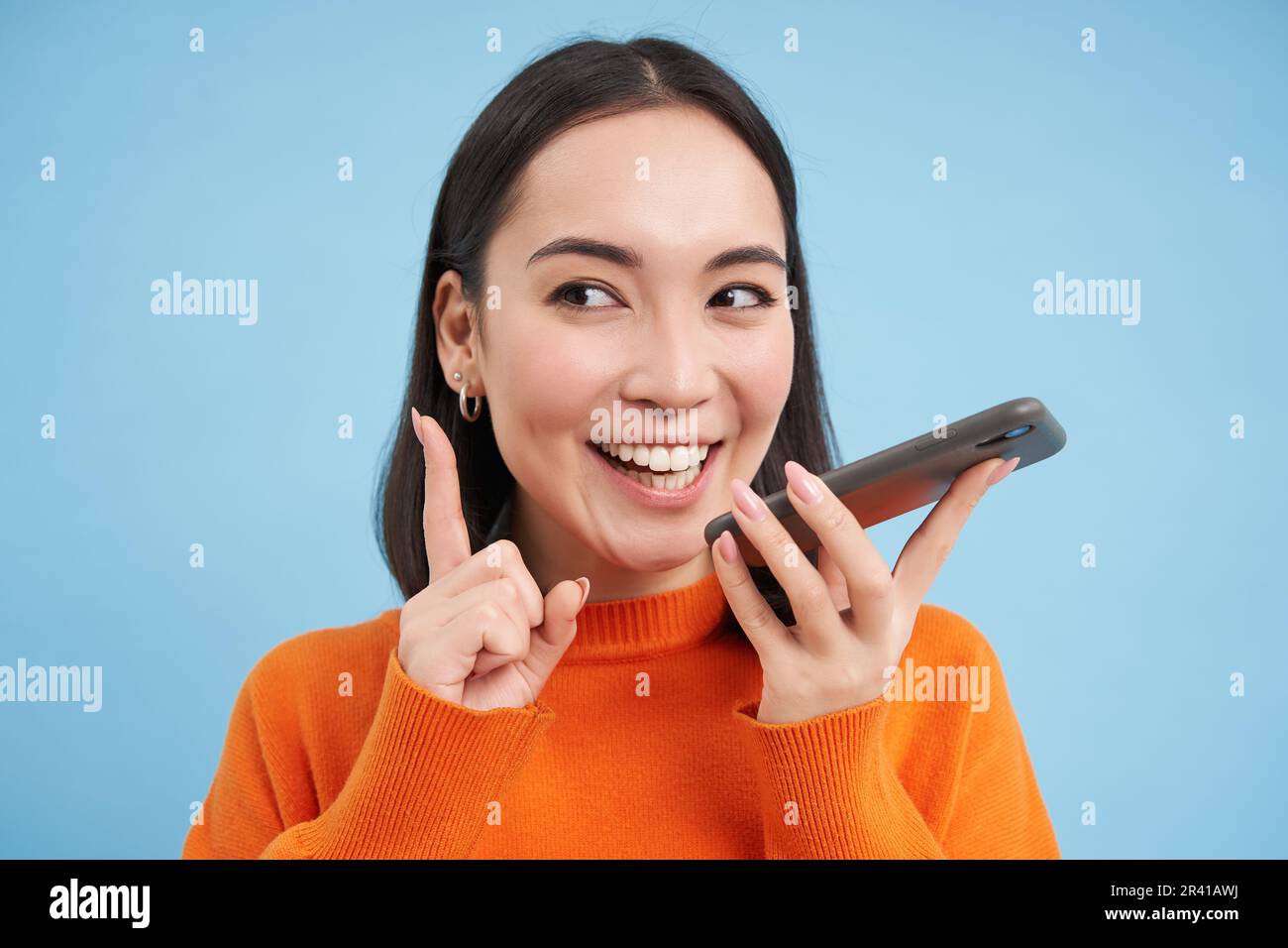 Portrait de la femme coréenne enregistre un message vocal sur l'application pour smartphone, parle sur l'orateur, traduit son discours sur l'application mobile, Blue ba Banque D'Images