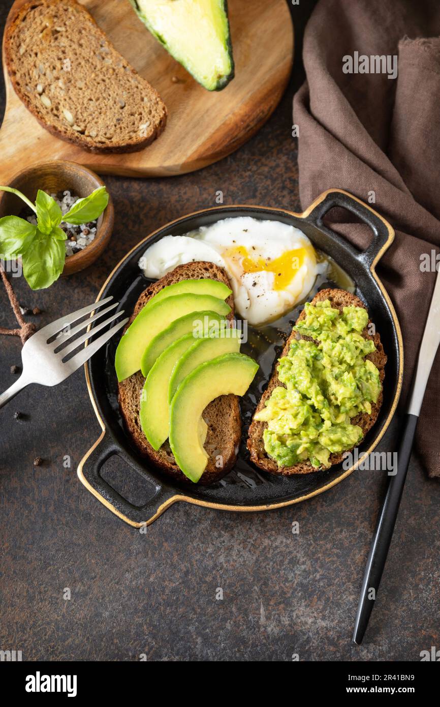 Pain complet toast coupé en tranches d'avocat et œuf poché sur fond de pierre. Concept de petit déjeuner sain, sandwich avec avocat et Banque D'Images