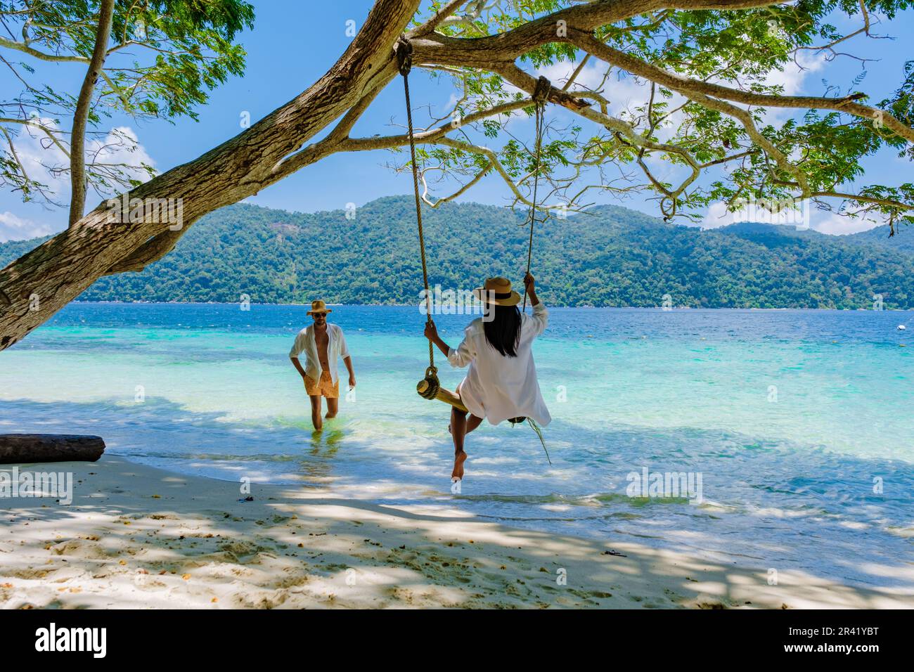 Un couple d'hommes et de femmes sont sur la plage avec une balançoire à corde Banque D'Images