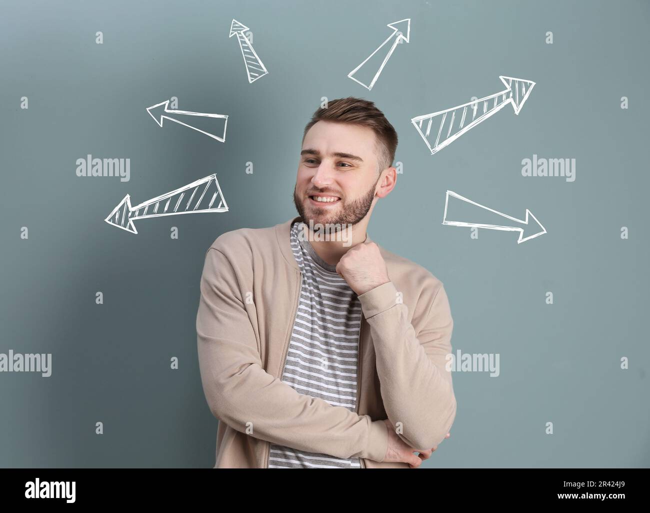 Choix dans la profession ou dans d'autres domaines de la vie, concept. Prise de décision, jeune homme entouré de flèches dessinées sur fond gris Banque D'Images
