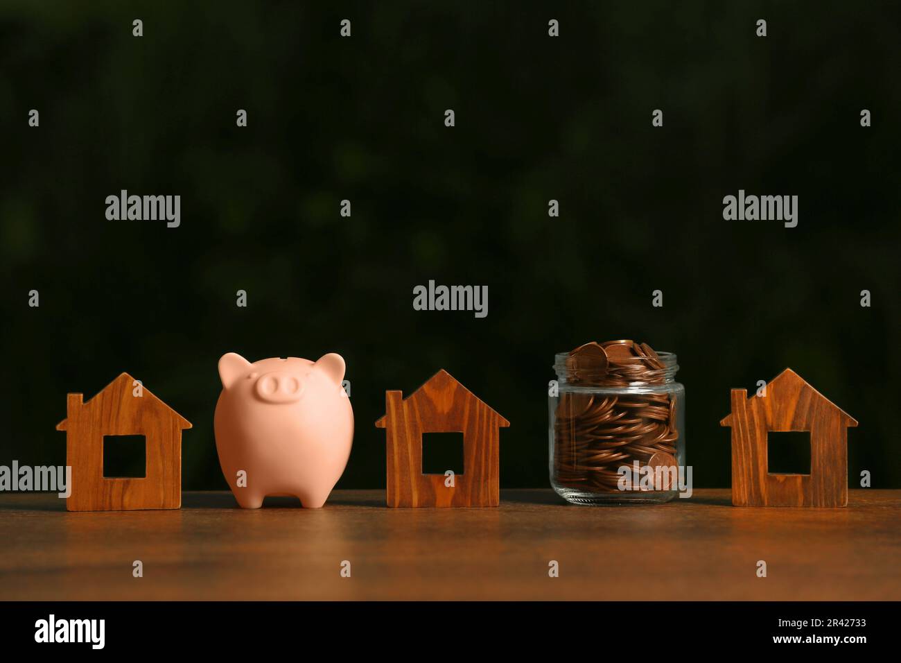 Tirelire, pot de pièces et modèles de maison sur table en bois Banque D'Images