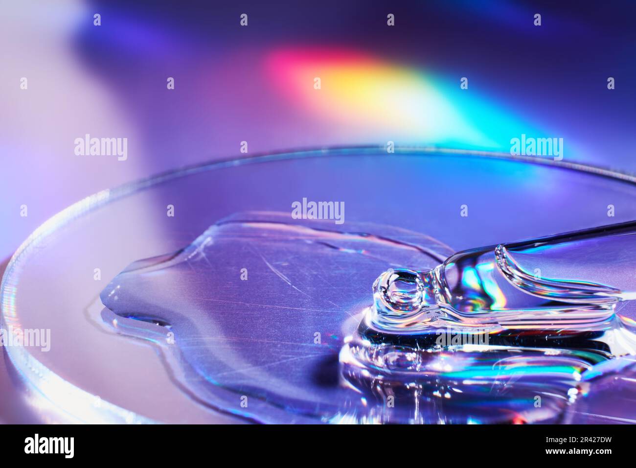 Pipeter avec un échantillon de produit cosmétique dans une boîte de Petri sur fond holographique, reflets irisés, foyer sélectif Banque D'Images