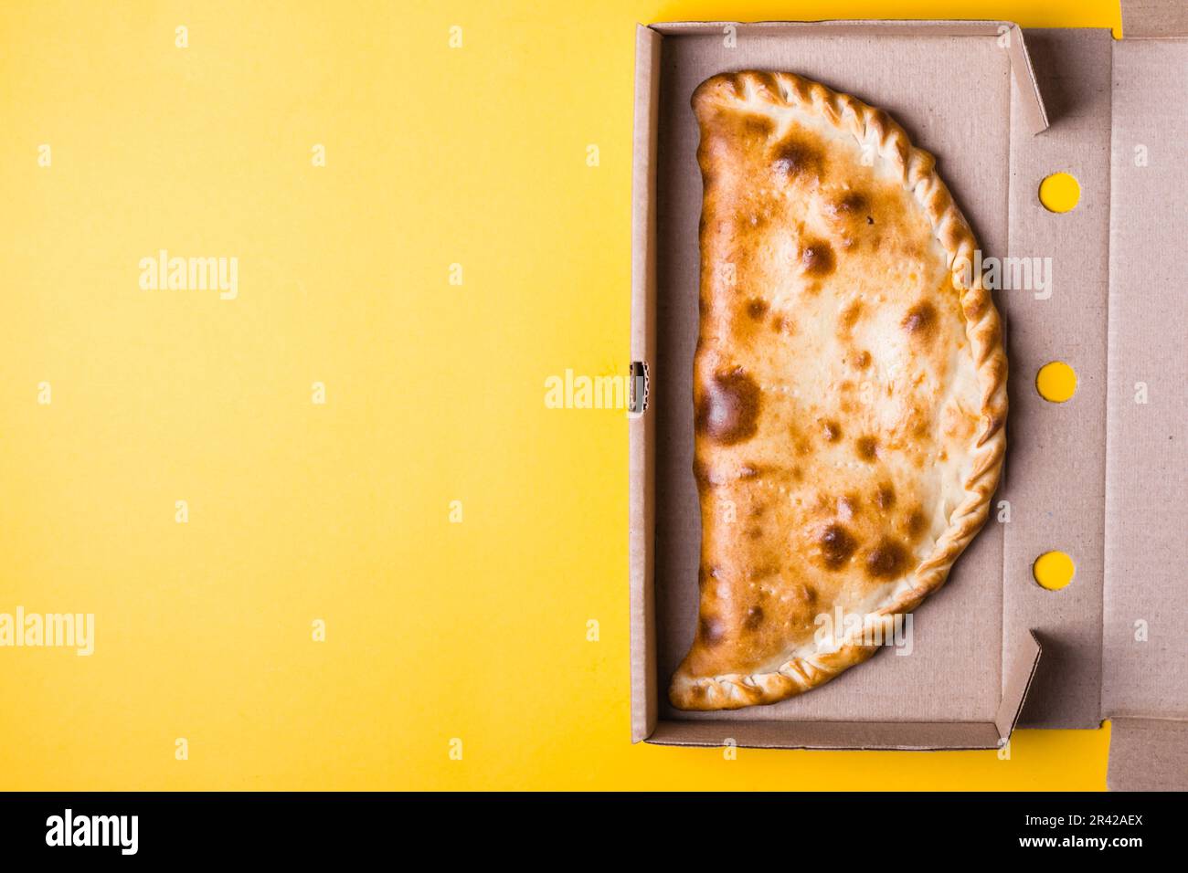 Fermeture de la zone de calzone de pizza dans la boîte d'emballage sur fond jaune Banque D'Images