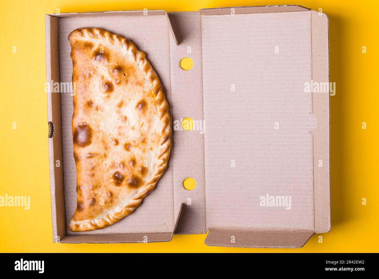 Fermeture de la zone de pizza dans une boîte d'emballage sur fond jaune Banque D'Images