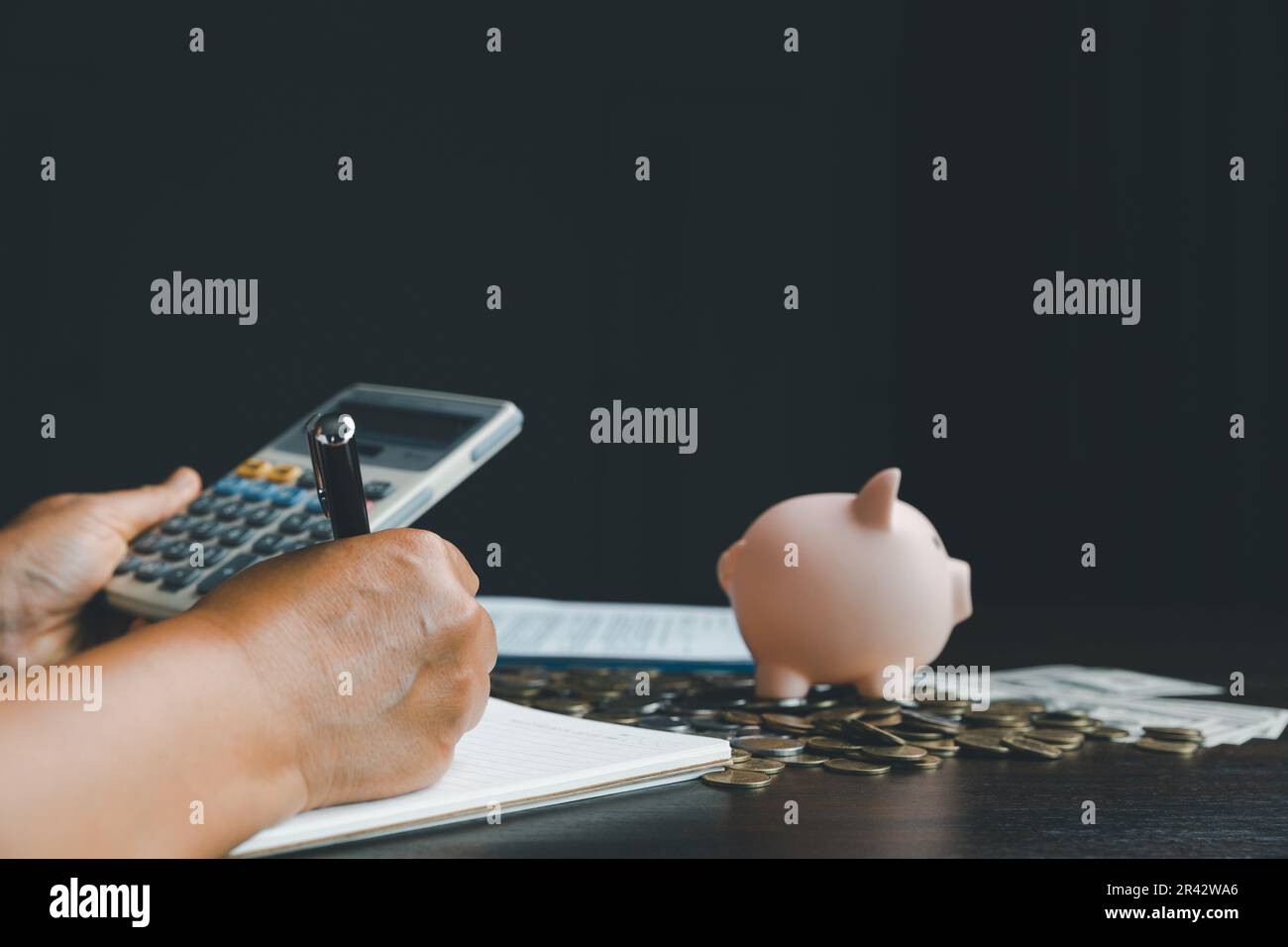 Femme d'affaires prendre note avec la banque de piggy sur fond de table en bois, économiser de l'argent richesse et concept financier, finance, investissement, plan financier Banque D'Images