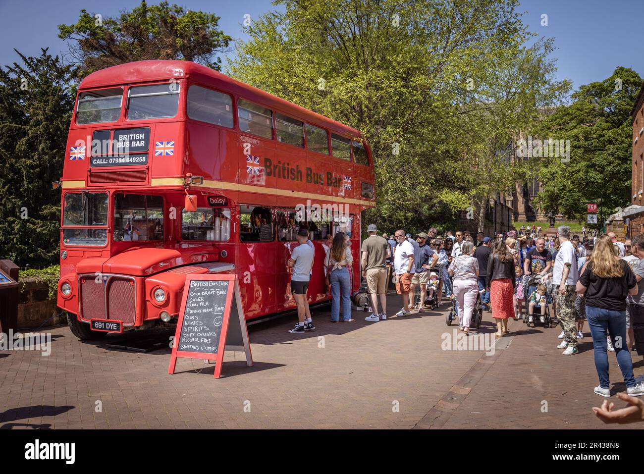 Les gens font la queue pour acheter un verre au British bus Bar, un bus à impériale rouge réaffecté, pendant le Lichfield Food Festival. Banque D'Images