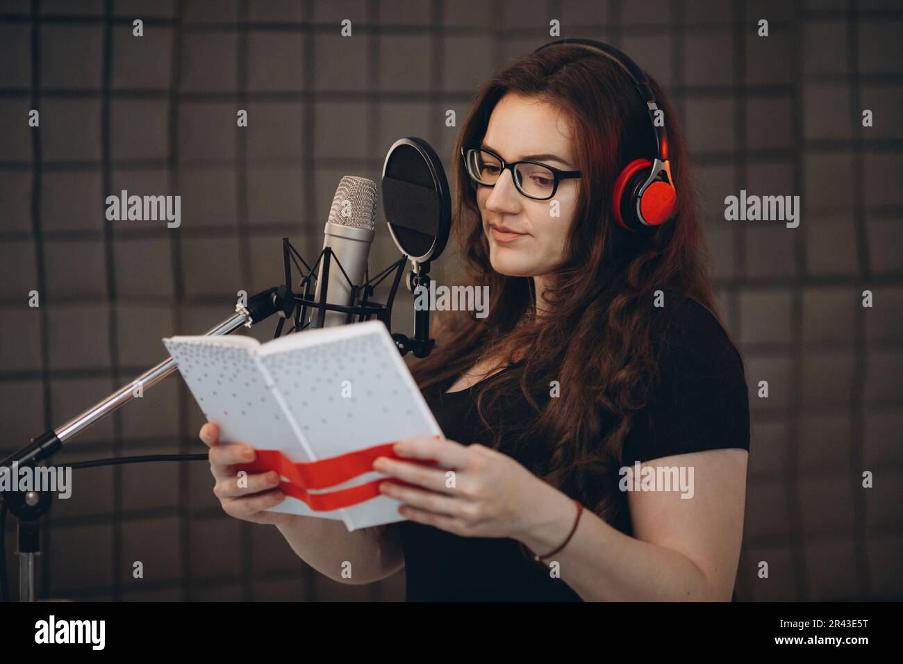 Artiste vocal professionnelle féminine avec casque parlant sur le micro pendant le doublage ou la voix off. Radio en ligne et concept de baladodiffusion. Banque D'Images