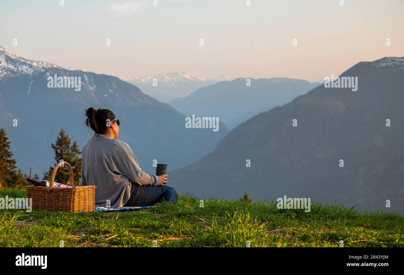 Vue arrière des femmes qui pique-niquent dans les montagnes au coucher du soleil. Banque D'Images