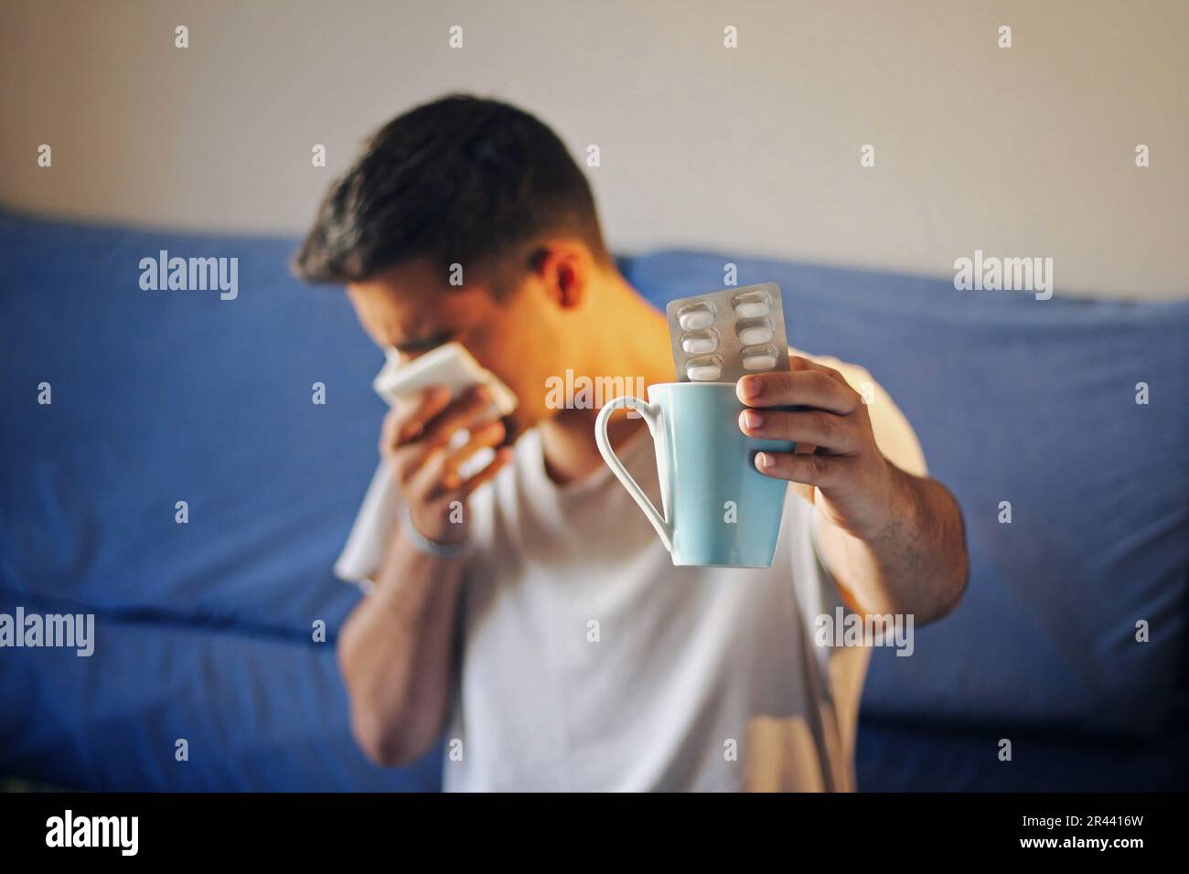 Homme froid assis sur le canapé avec des médicaments. Banque D'Images Homme froid assis sur le canapé avec des médicaments. Banque D'Images
