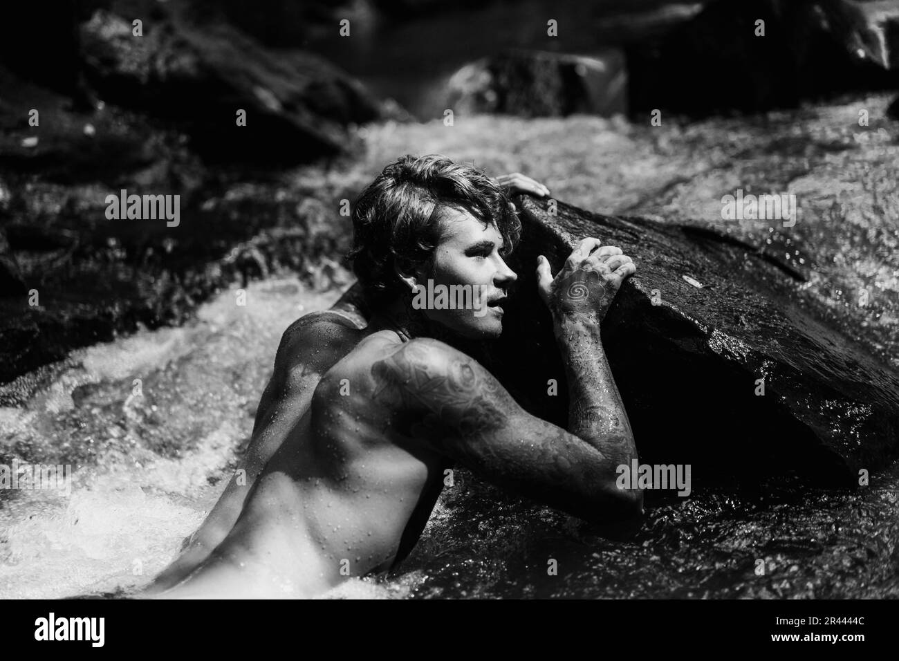 Un jeune homme tatoué nage dans une rivière de montagne à Bali. Banque D'Images