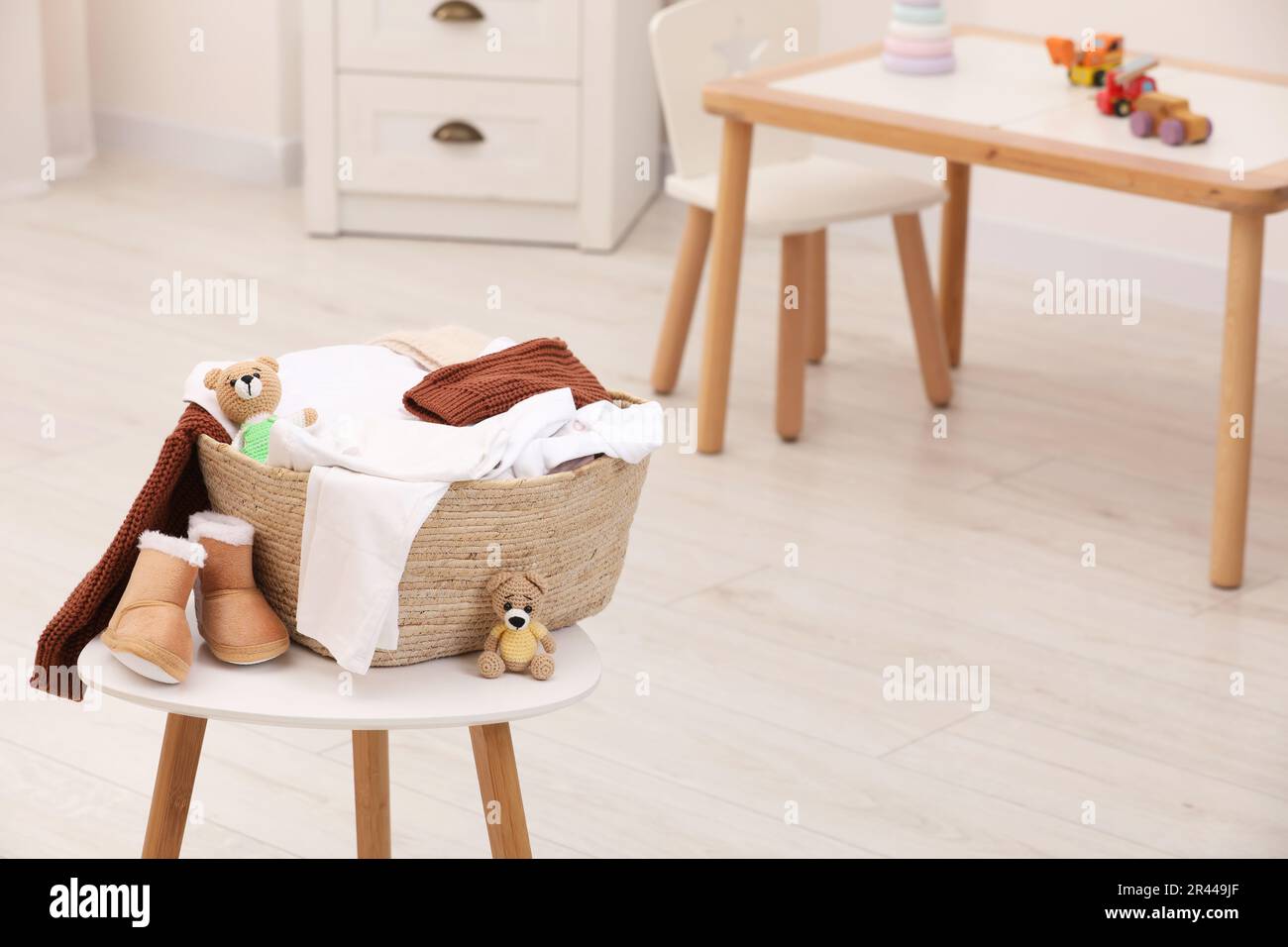 Panier à linge avec vêtements pour bébés, chaussures et jouets en crochet  sur table en bois blanc dans la chambre d'enfant, espace pour le texte  Photo Stock - Alamy