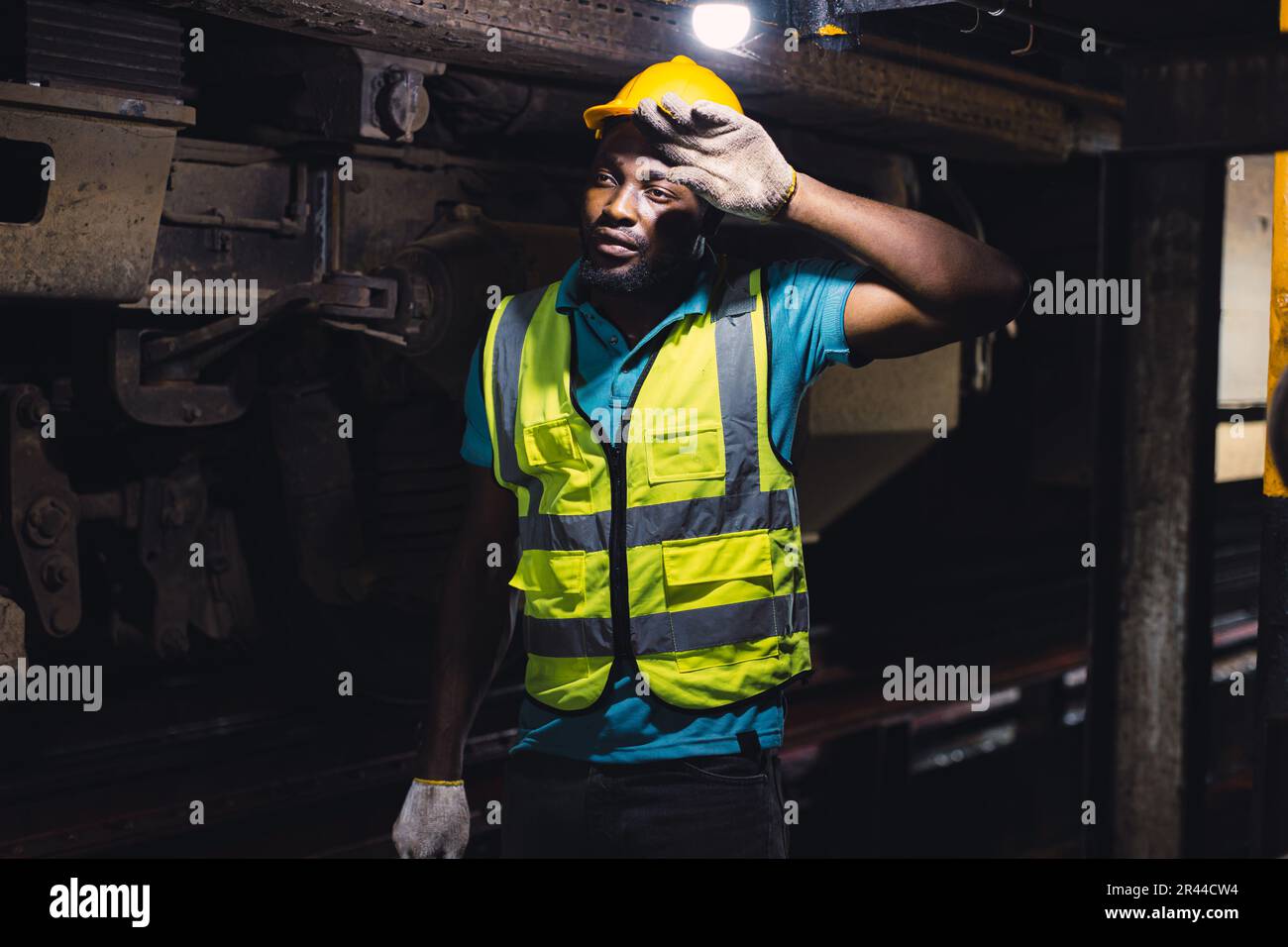 Travailleur fatigué épuisé travail dur, mécanicien d'ingénieur de locomotive sentir la fatigue travail dans la station de réparation de train machine de travail sale chaud Banque D'Images
