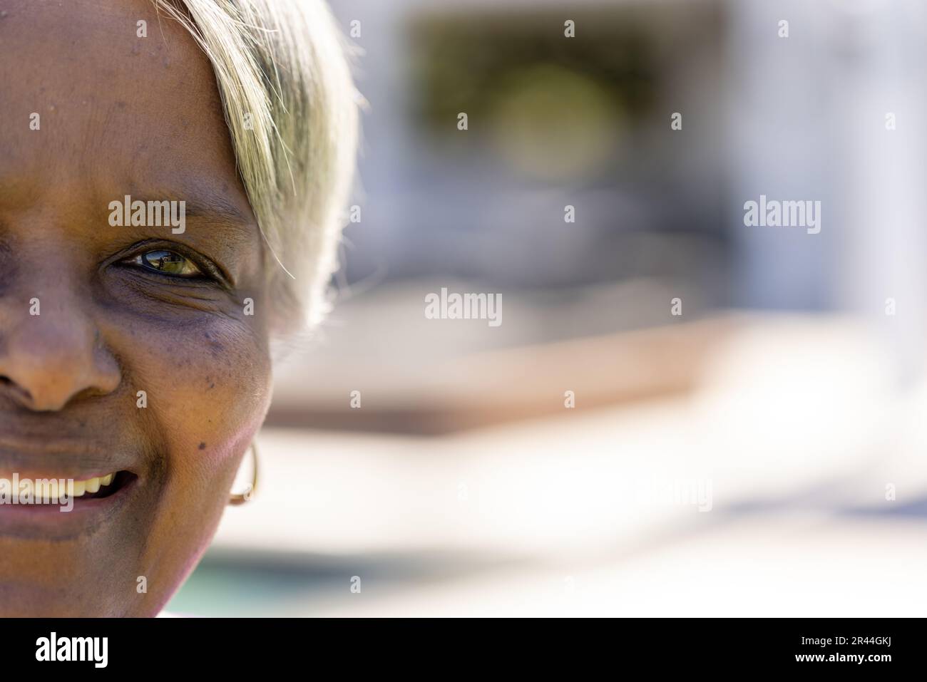 Demi portrait de la femme biraciale aînée heureuse souriant dans le jardin ensoleillé, espace copie Banque D'Images