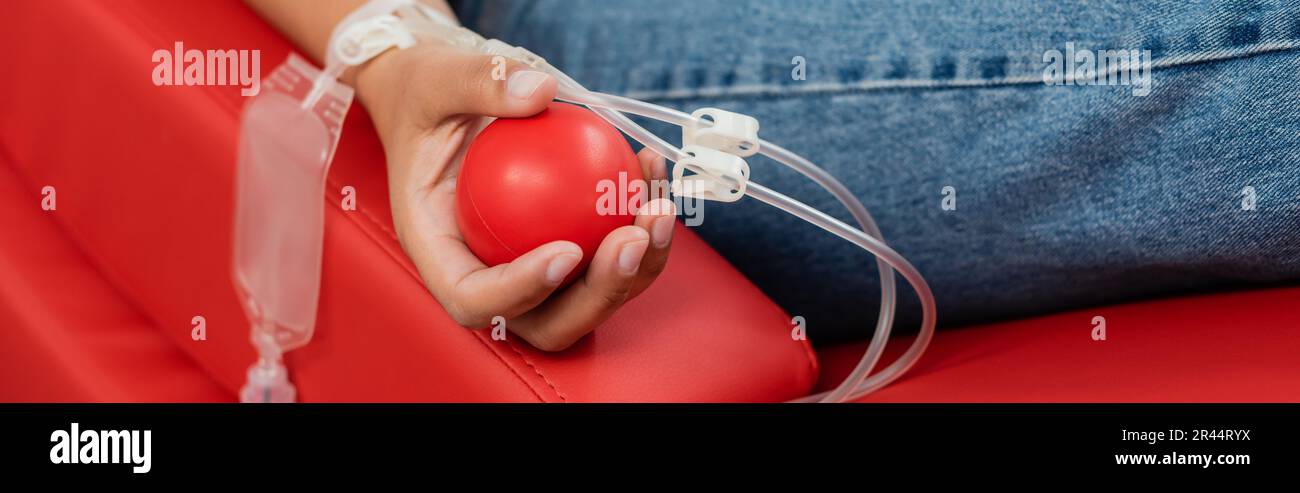 vue rognée d'une femme multiraciale avec kit de transfusion et boule de caoutchouc sur une chaise médicale confortable et ergonomique tout en donnant du sang dans l'hope Banque D'Images