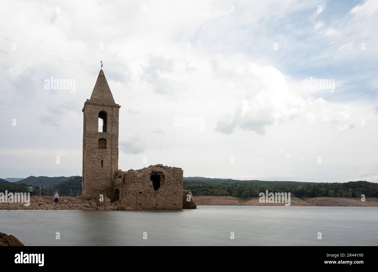 Photographie en exposition longue de l'église de Sant Roma de Sau dans le réservoir de Sau avec de l'eau à effet de soie avec les gens Banque D'Images