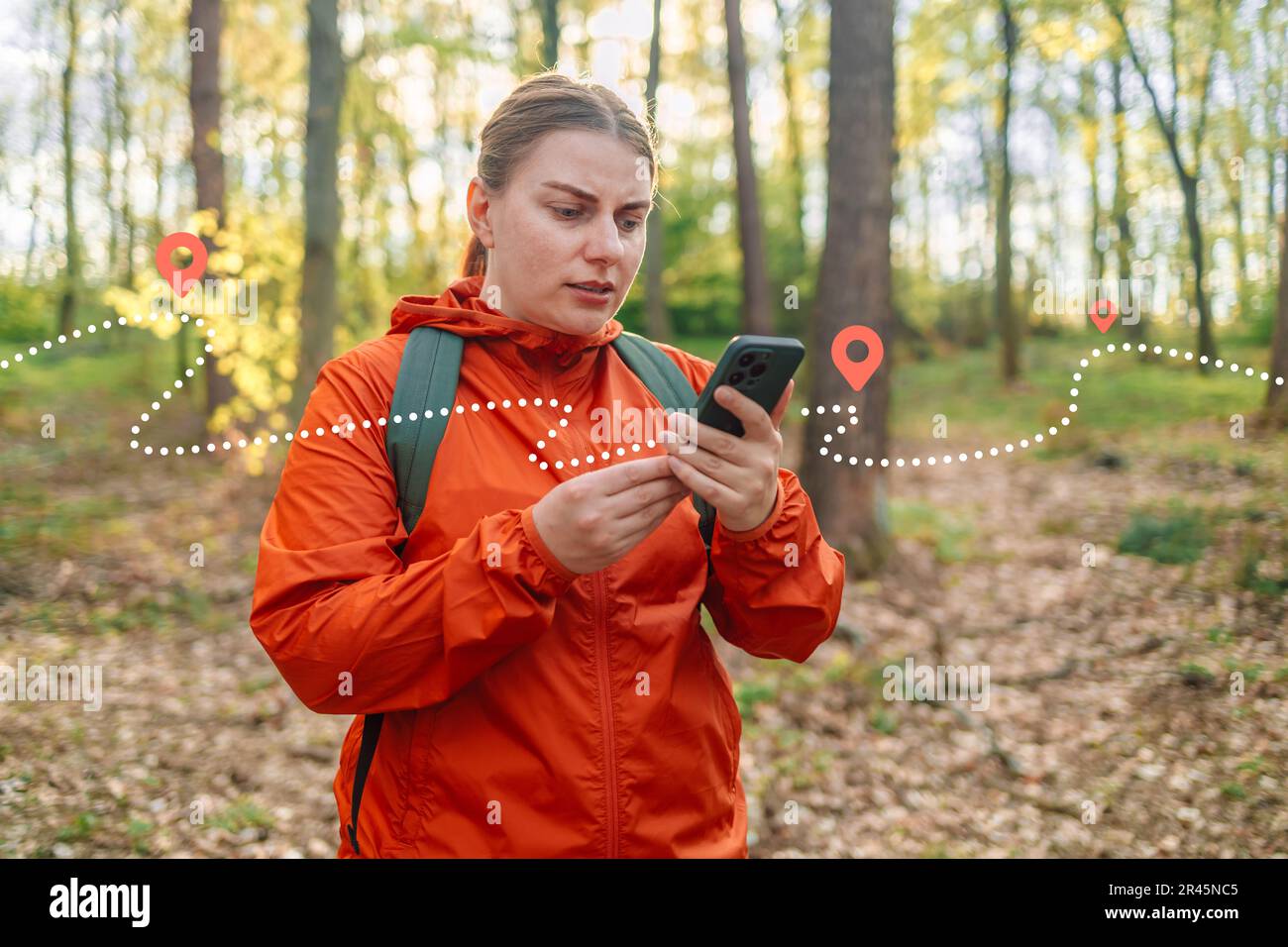 Belle femme triste dans une veste de sport rouge vif utilisant une  application mobile pour naviguer dans une forêt de printemps. Touriste  essayant de trouver le meilleur moyen. Actif Photo Stock -