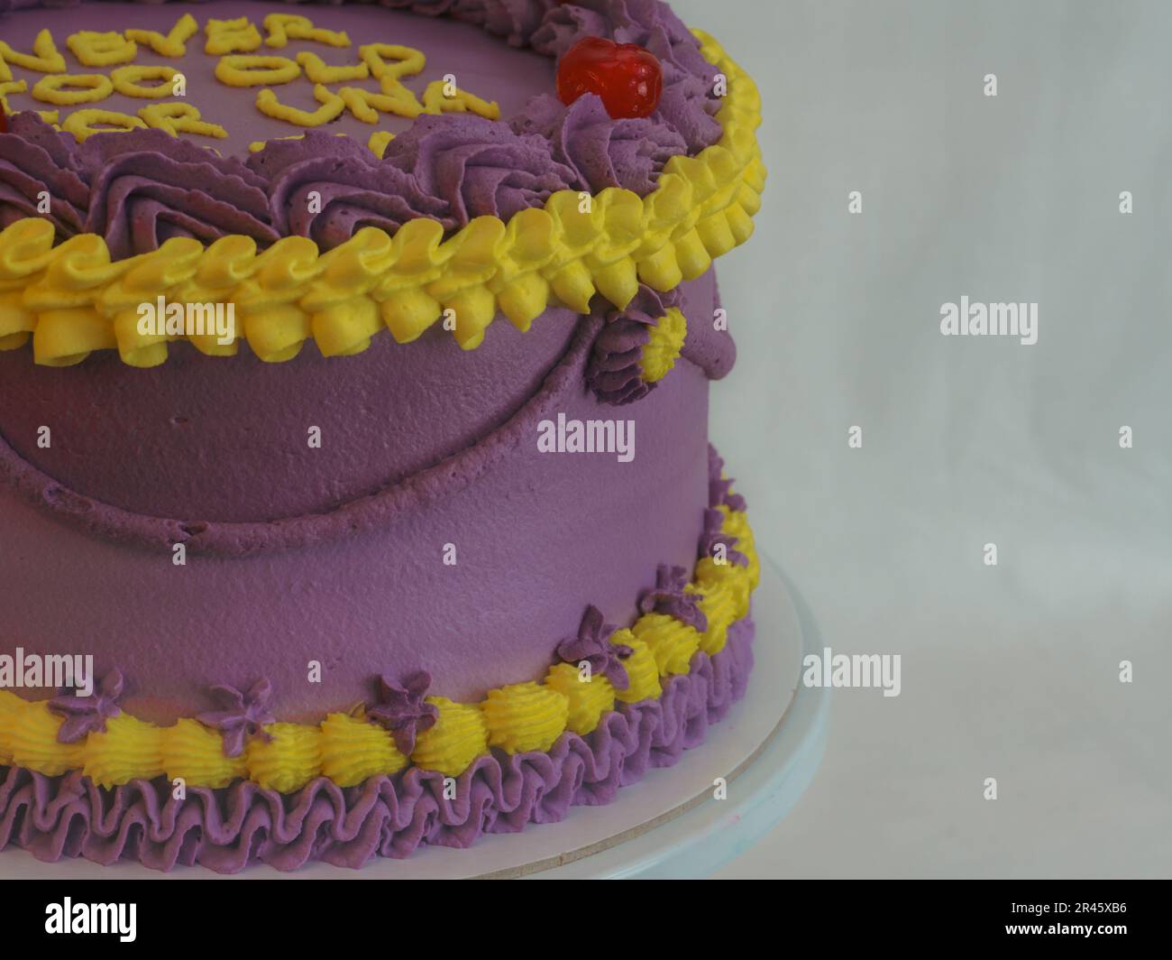 gâteau ciryndrical violet givré jaune classique avec garniture de message texte sur fond blanc studio. Gâteau superposé romantique. Banque D'Images