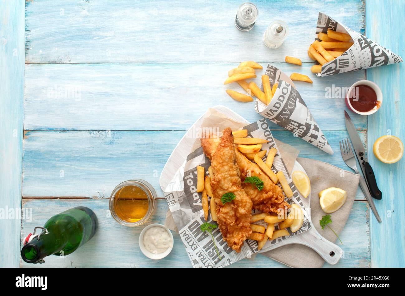 Plats traditionnels à emporter avec du poisson et des frites, emballés dans le journal avec de la bière Banque D'Images
