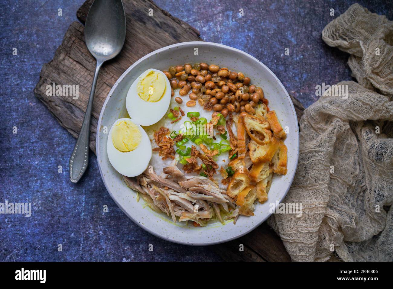 Bubur ayam, porridge de riz indonésien avec poulet râpé et servi avec des œufs durs durs durs, des craquelins de crevettes et de la sambal de pâte de Chili Banque D'Images