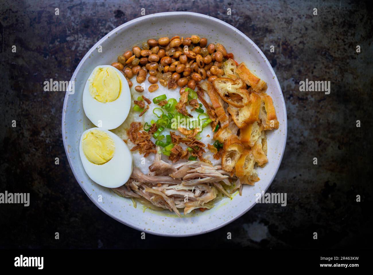 Bubur ayam, porridge de riz indonésien avec poulet râpé et servi avec des œufs durs durs durs, des craquelins de crevettes et de la sambal de pâte de Chili Banque D'Images