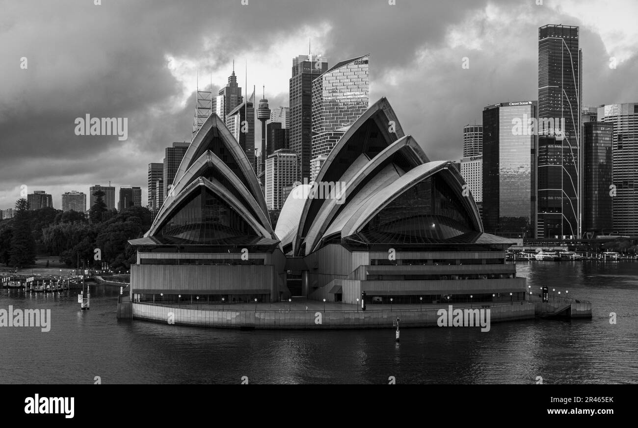 Une photo en niveaux de gris de l'Opéra de Sydney avec la Tour de Sydney en arrière-plan depuis le port. Banque D'Images