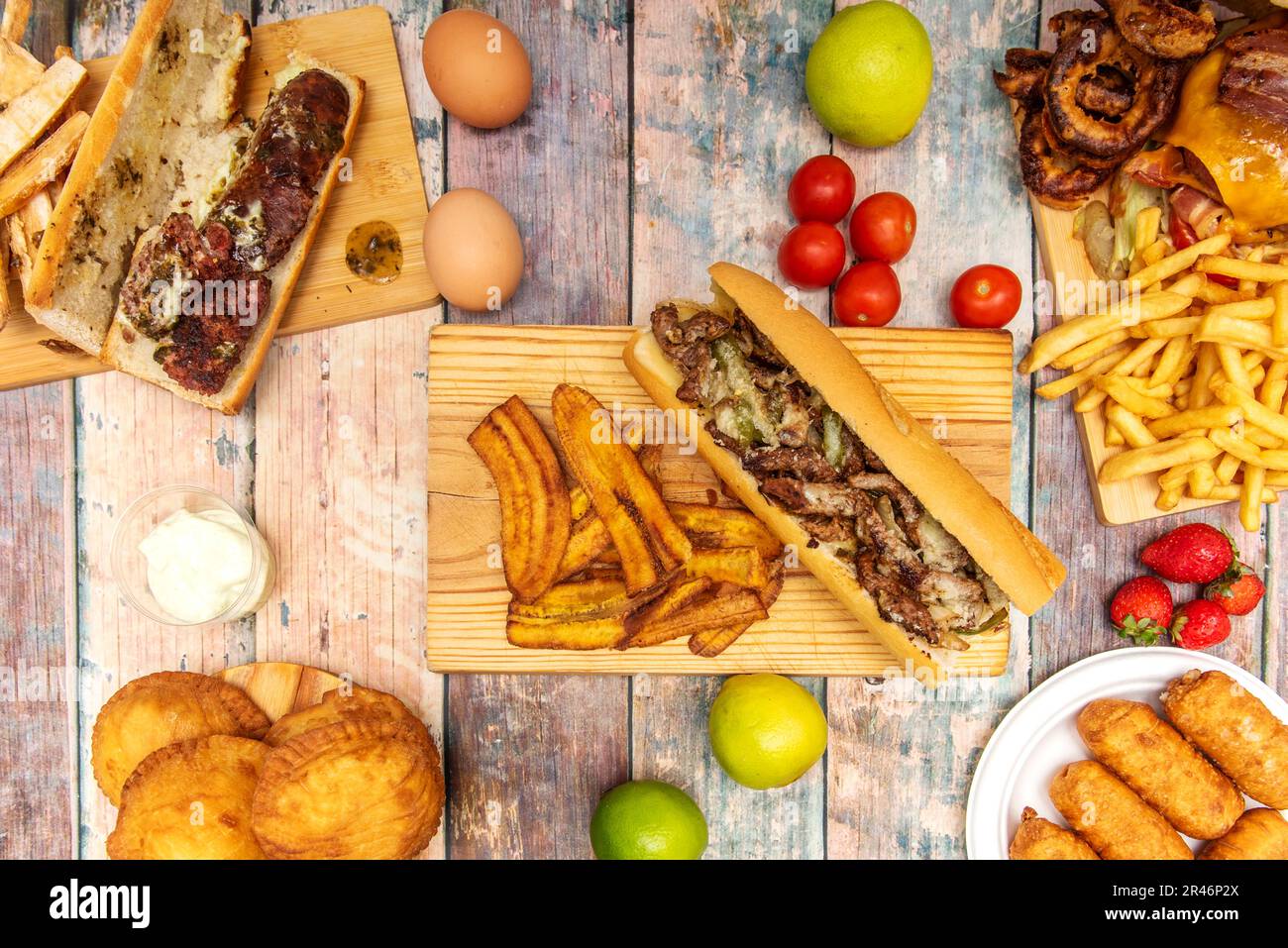 ensemble de plats de restauration rapide latins avec un sandwich au bœuf avec des morceaux de plantain frits, des fruits, des légumes et des empanadas Banque D'Images