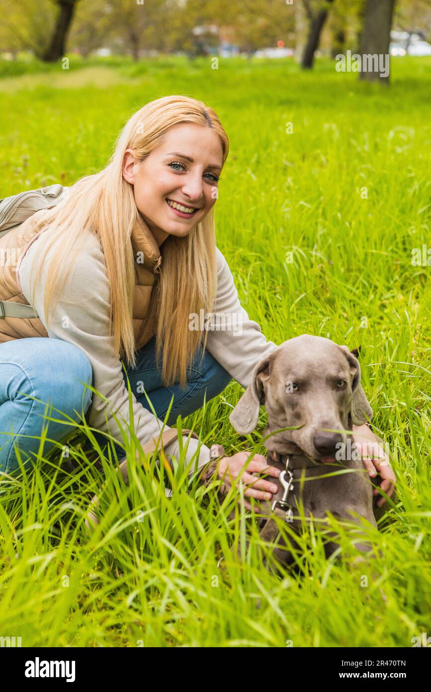 Portrait de weimaraner avec sa maîtresse dans le parc. Jeune femme marchant le chien. Concept de loisirs et de vie saine dans la nature Banque D'Images