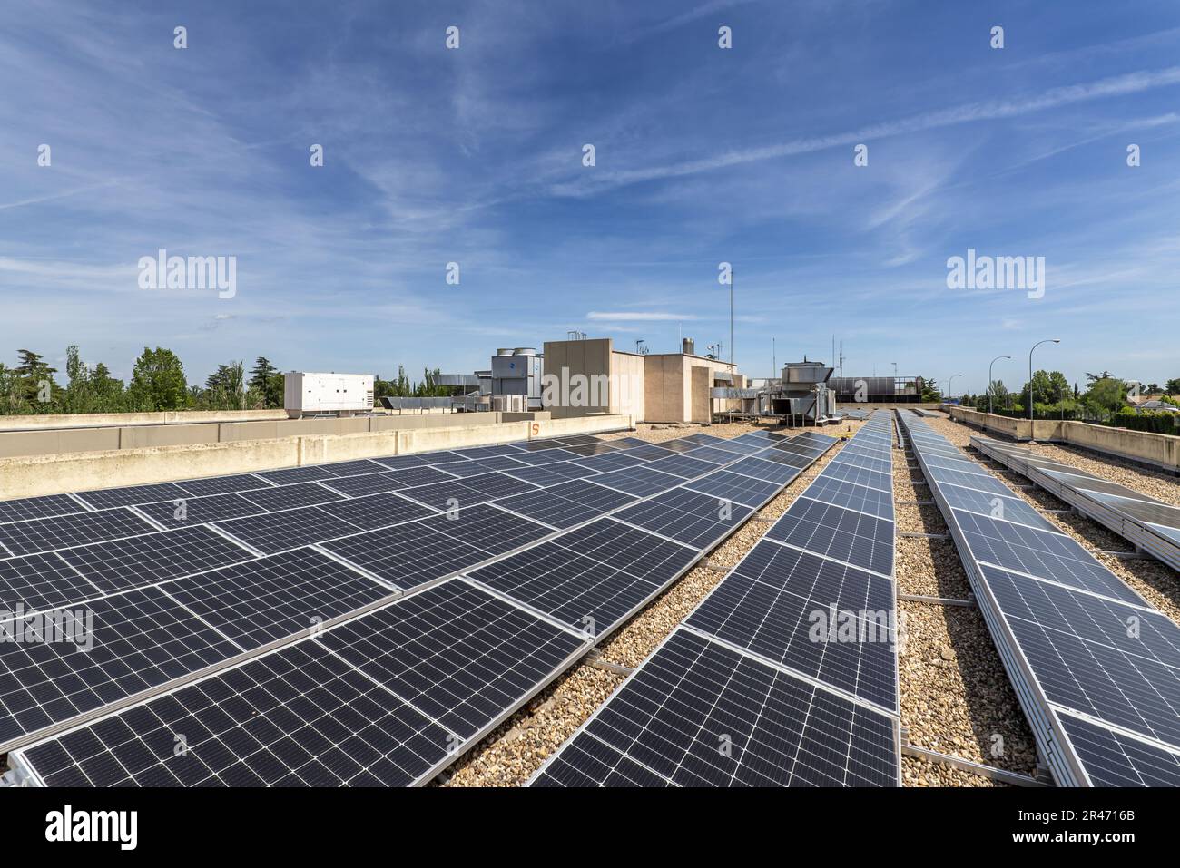 Alignement des panneaux solaires récemment installés sur le toit d'un immeuble de bureaux avec le sol recouvert de gravier Banque D'Images