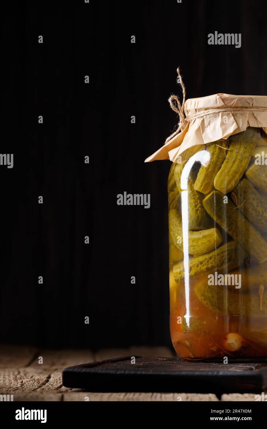 Concombres marinés dans un pot en verre fermé sur une surface en bois avec un espace pour le texte. Concombres en conserve faits maison dans un pot Banque D'Images