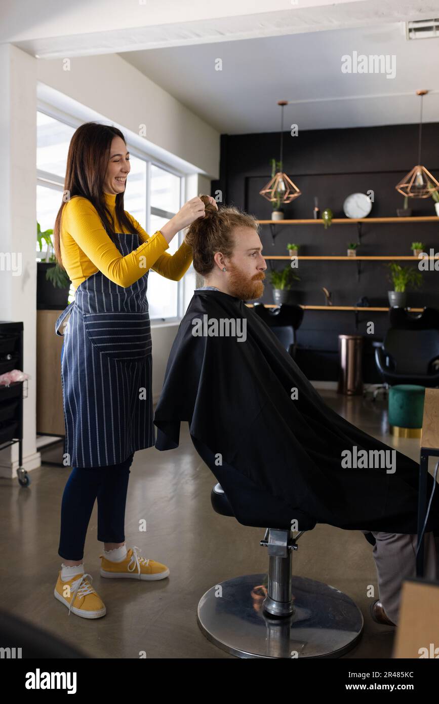 Happy caucasien femme coiffeur unmaning cheveux pain de long cheveux homme client au salon de coiffure Banque D'Images