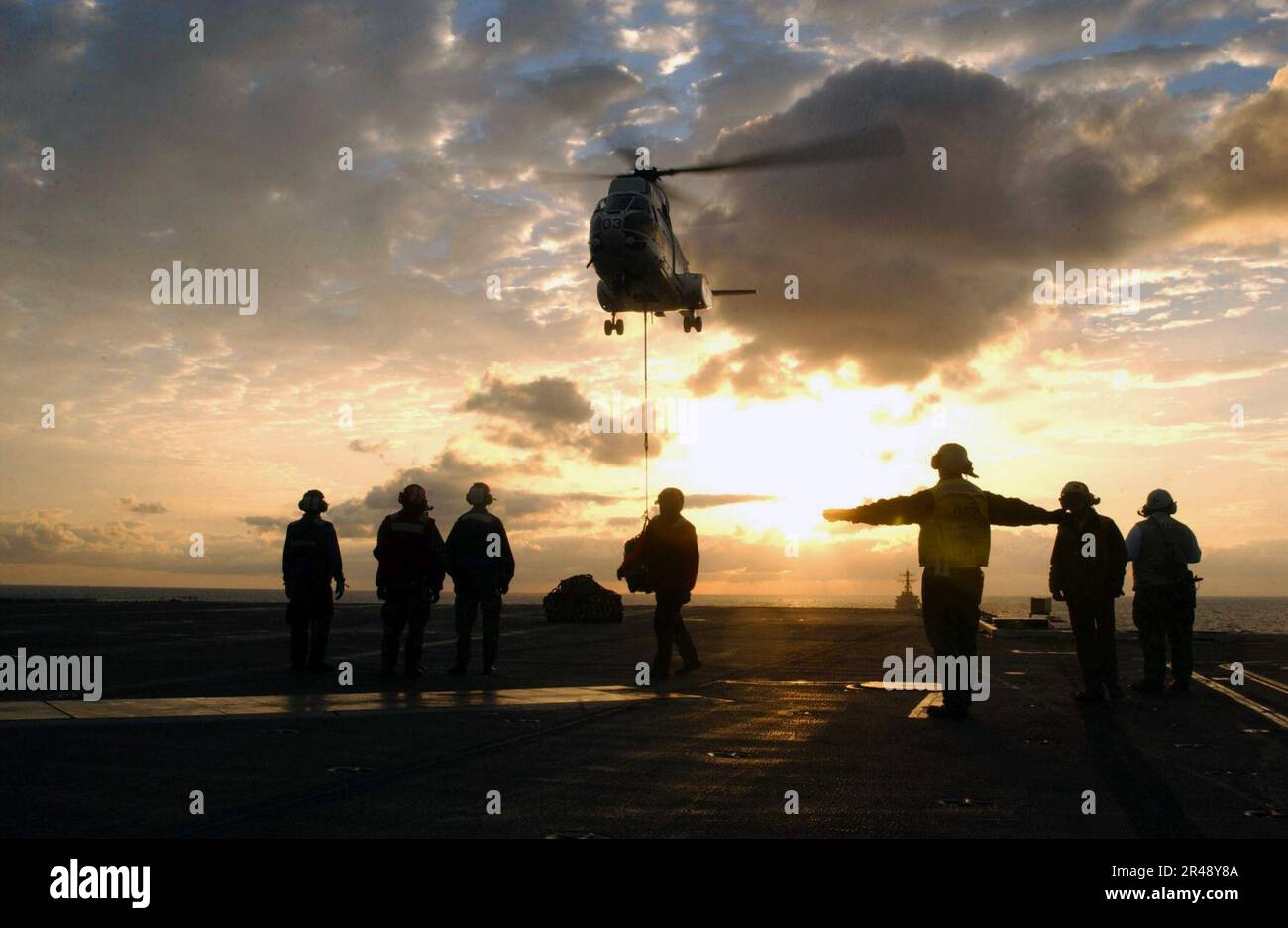 LES directeurs d'aéronefs DE la MARINE AMÉRICAINE guident un hélicoptère en position sur le pont de vol du navire Banque D'Images
