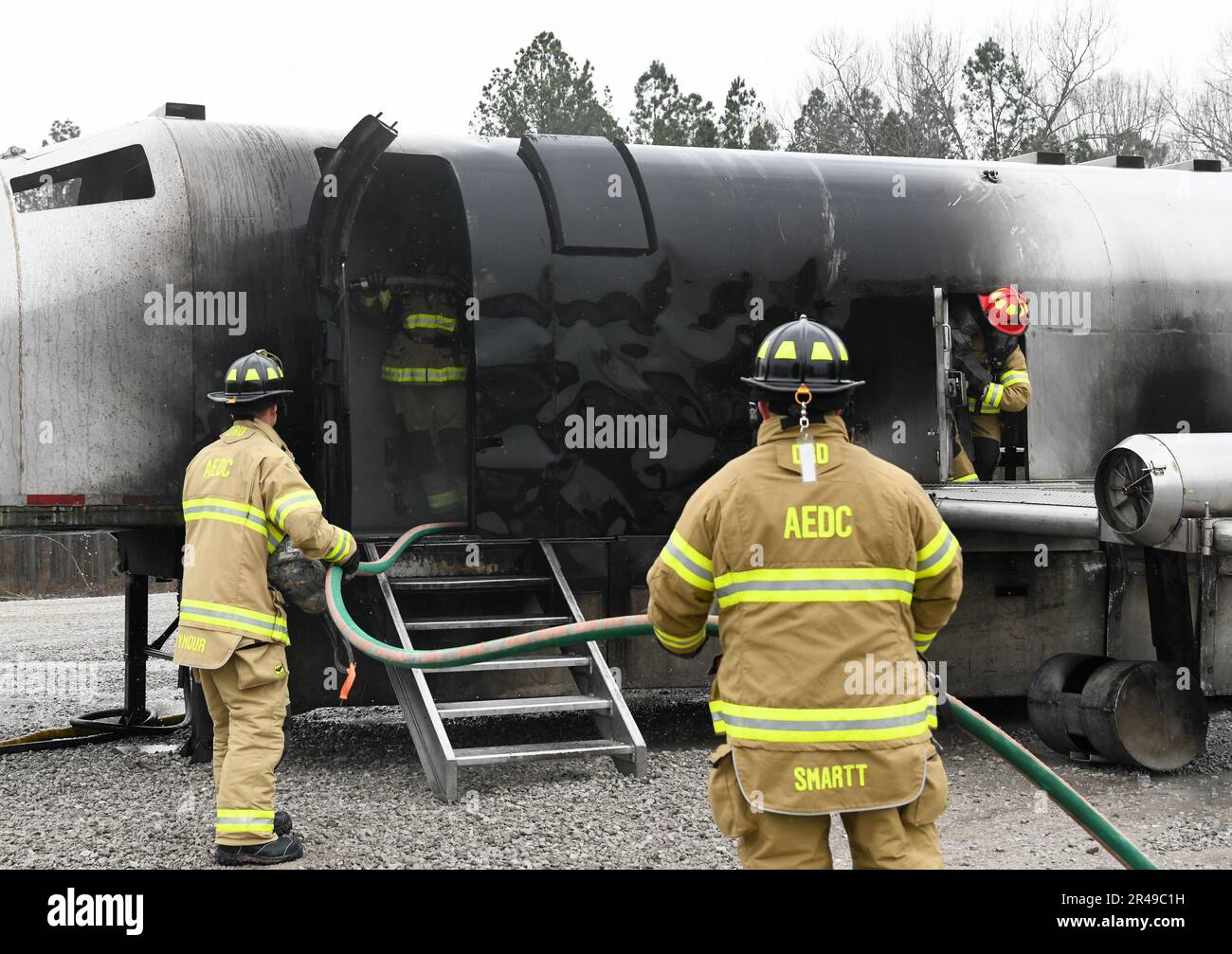 Le colonel Randel Gordon, à droite, Arnold Engineering Development Complex commandant, transporte un mannequin d'entraînement par une porte latérale d'un simulateur d'incendie d'avion à la base aérienne Arnold, au Tennessee, au 9 mars 2023. Devant le simulateur, Chevis Lee, pompier de la base aérienne Arnold, utilise une ligne de main pour combattre un incendie. Gordon a eu l'occasion de participer pour améliorer sa compréhension des compétences et des efforts nécessaires pour lutter contre le feu. Banque D'Images