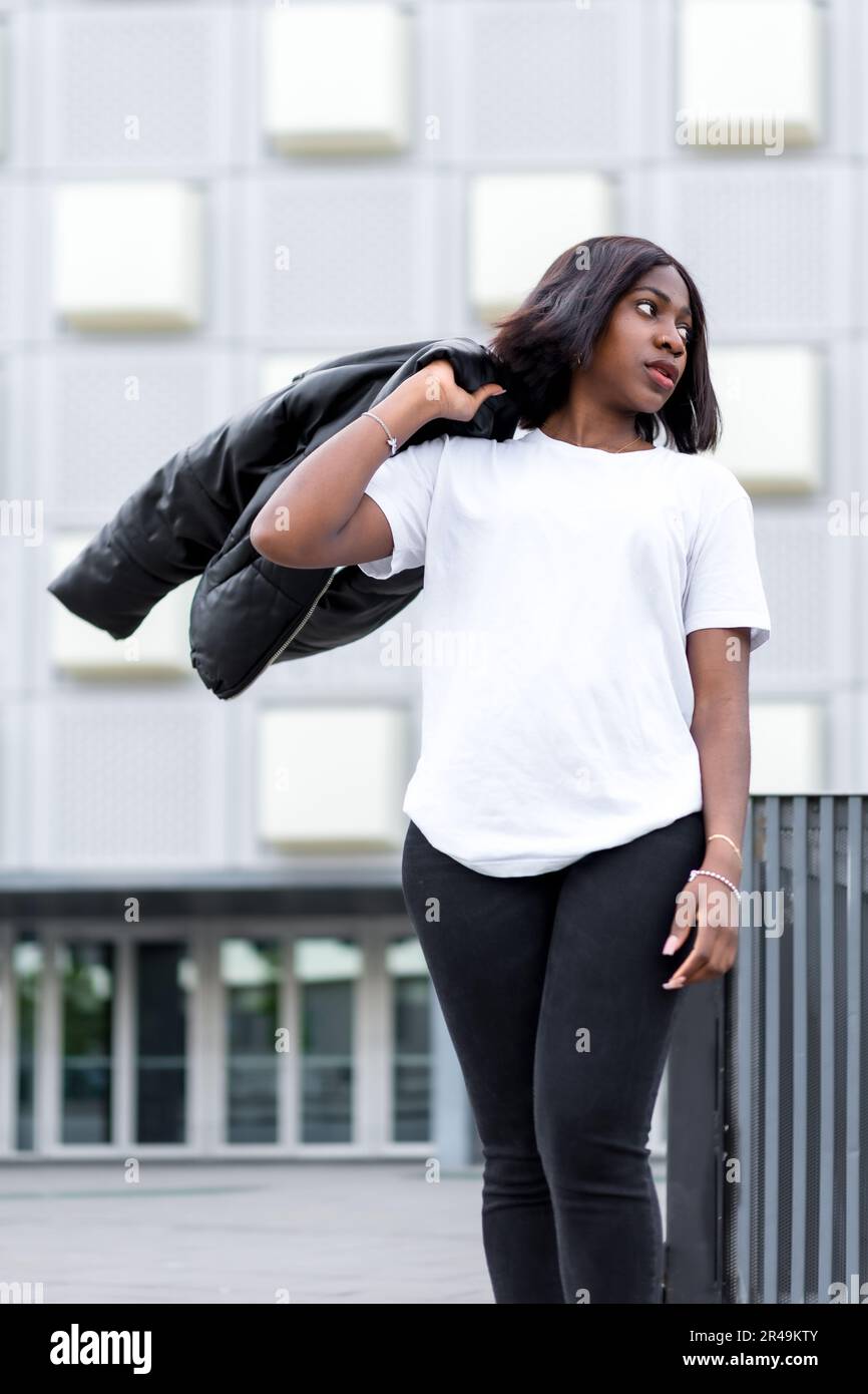 Une jolie femme noire se pose avec assurance dans une tenue decontractee portant un manteau noir Photo Stock Alamy
