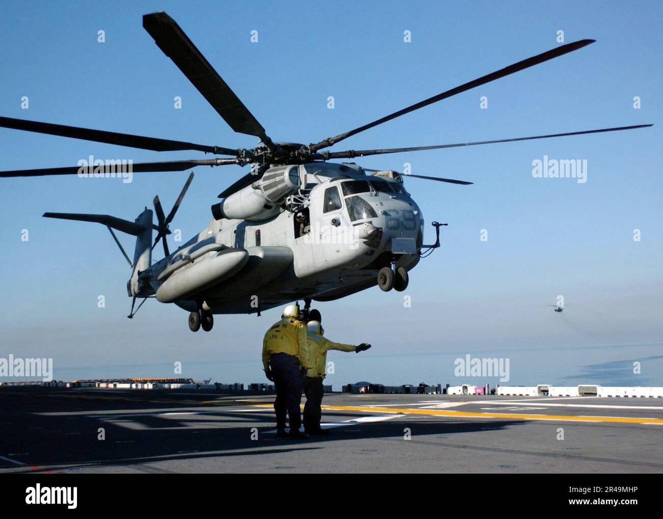 LES mates DE Boatswain DE L'AVIATION DE LA MARINE AMÉRICAINE dirigent un CH-53E « sea Stallion » lorsqu'il manœuvre pour atterrir sur le pont de vol du navire Banque D'Images