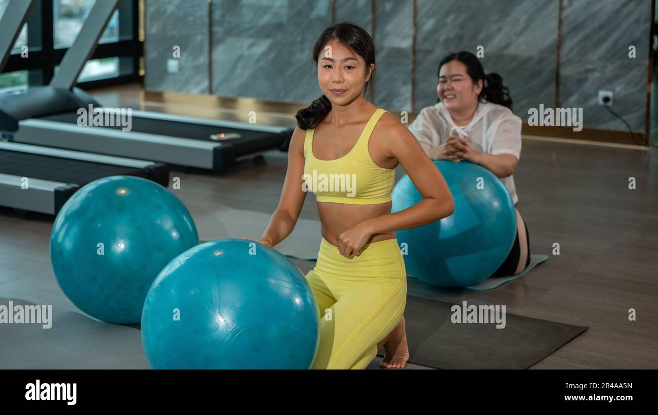 Humour dans les sports ball Yoga. FAT Asian femme avec son professeur d'instruteur de yoga formation en gymnastique avec le ballon de fitness. Femme asiatique sportive faisant de l'exercice Banque D'Images