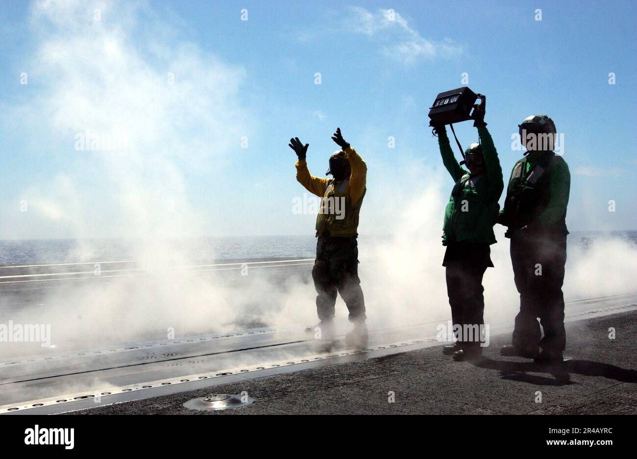 US Navy un directeur d'avion guide un avion en position de lancement alors que les Mates de Aviation Boatswain vérifient son poids avant le lancement depuis le pont de vol à bord du porte-avions de la classe Nimitz USS Ron. Banque D'Images