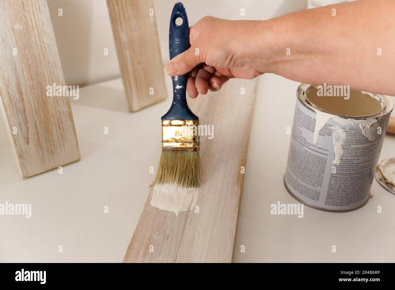 Les mains de femme peignent en blanc sur une planche de bois avec un pinceau Banque D'Images