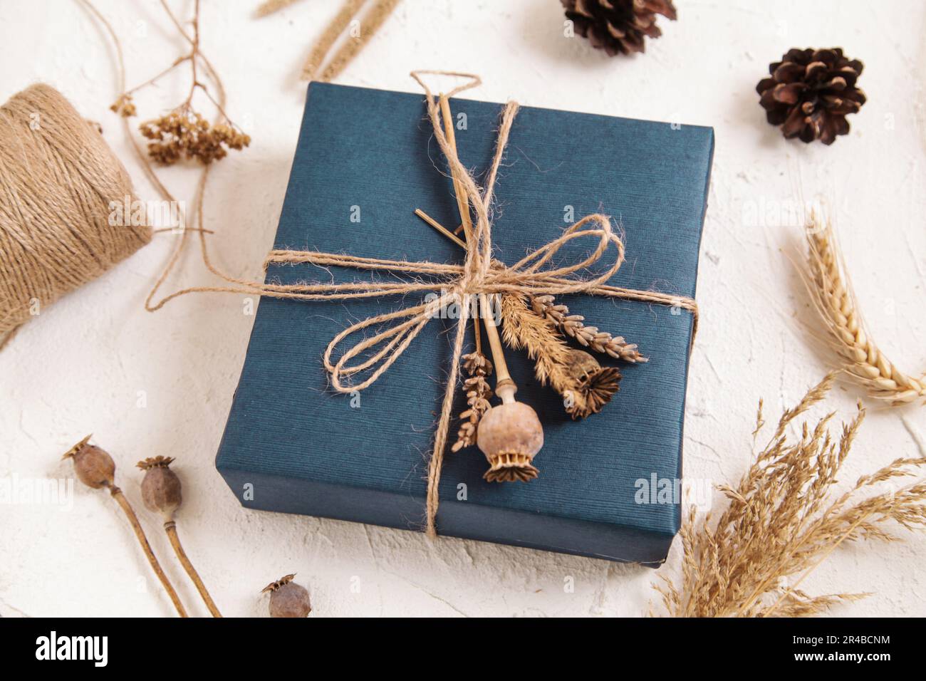 Boîte cadeau faite à la main dans un emballage bleu foncé, têtes de graines de pavot, fleurs séchées. Cadeau pour homme. Fleuriste, herbier artisanal. Couleurs naturelles. vue de dessus. copie s Banque D'Images
