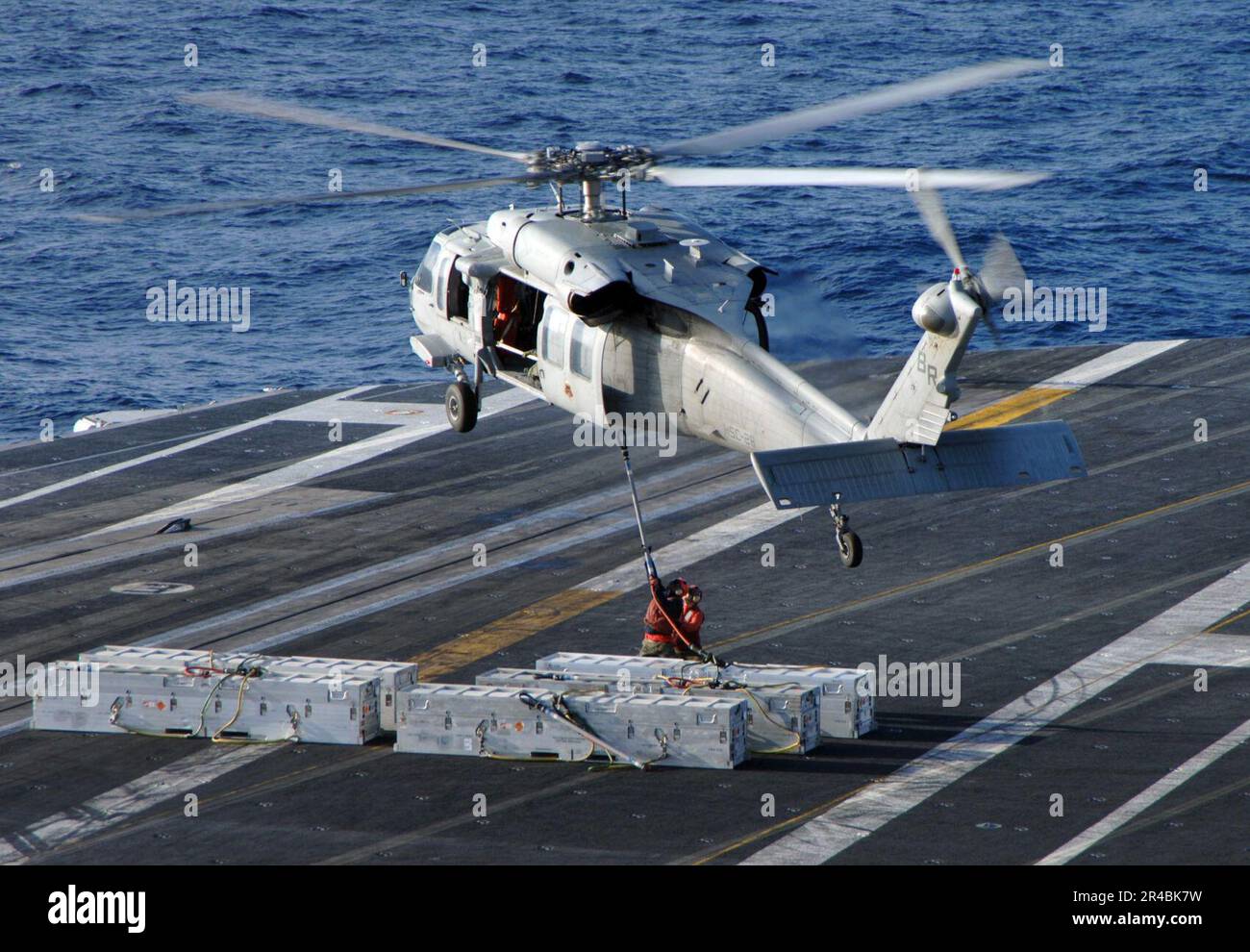 LES officiers de l'aviation DE LA Marine AMÉRICAINE attachent des munitions  à un hélicoptère MH-60s Seahawk, affecté au 2e Escadron de combat en mer  (HSC-28), sur le pont de vol du porte-avions