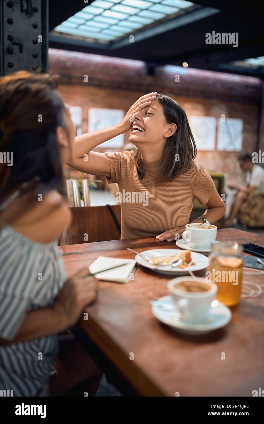 Deux jeunes amies au café s'amuser et rire, parler. Jeune belle femme appréciant le temps du café. Banque D'Images