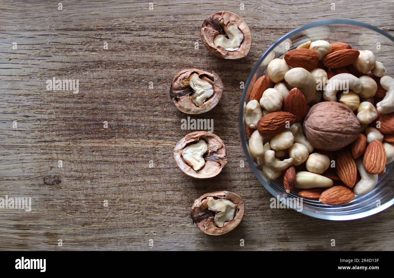 Variété de noix pelées dans un bol et quatre moitiés d'une noix sur un panneau en bois d'époque Banque D'Images