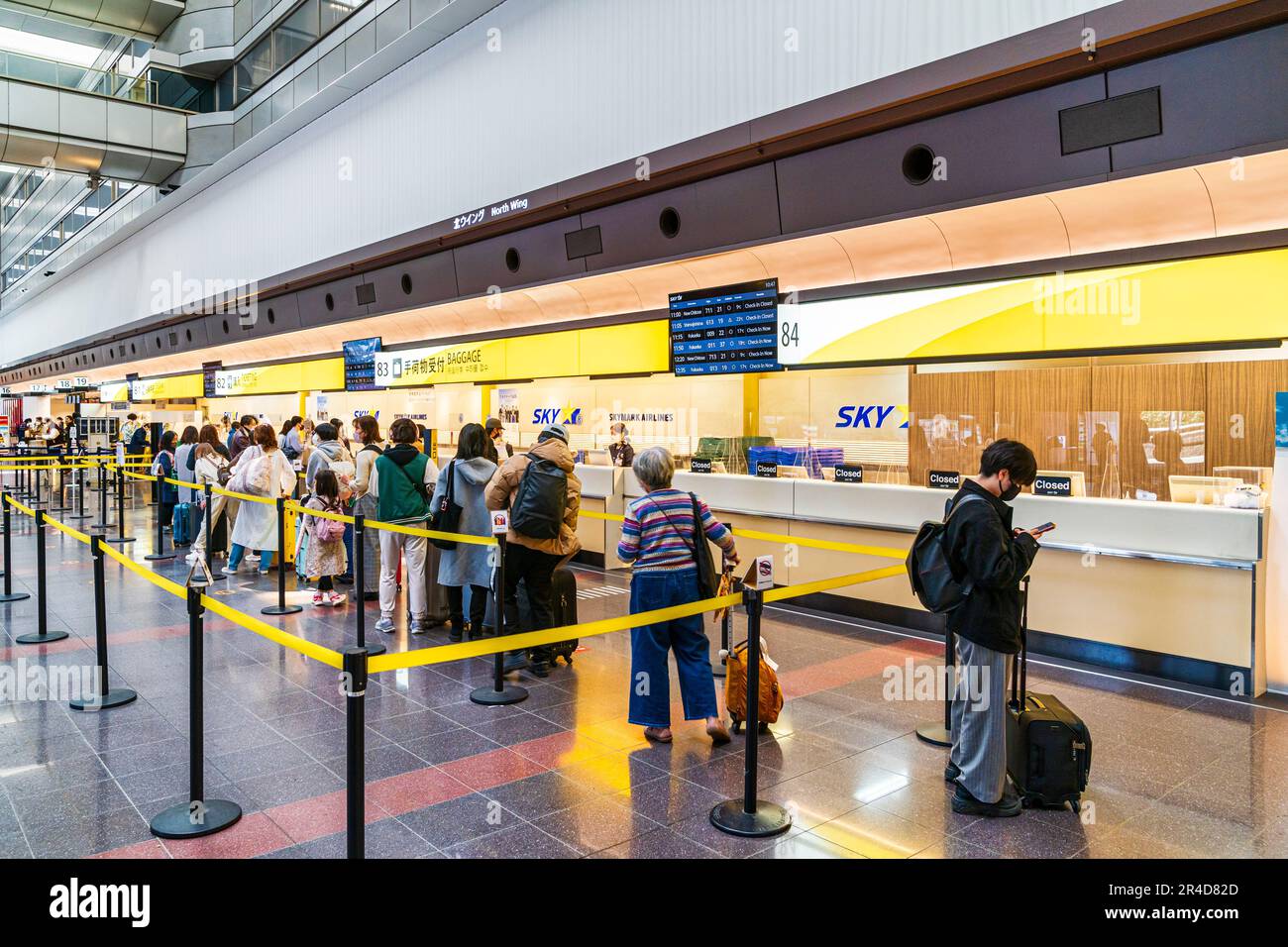 Les gens font la queue au comptoir d'enregistrement des bagages de Skymark Airlines à l'aile nord du terminal 1, à l'aéroport Haneda de Tokyo. Banque D'Images