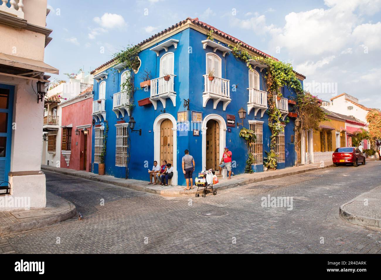 Les gens assis et errant à côté d'un bâtiment bleu clair d'angle dans la vieille ville de Cartagena Colombie Banque D'Images