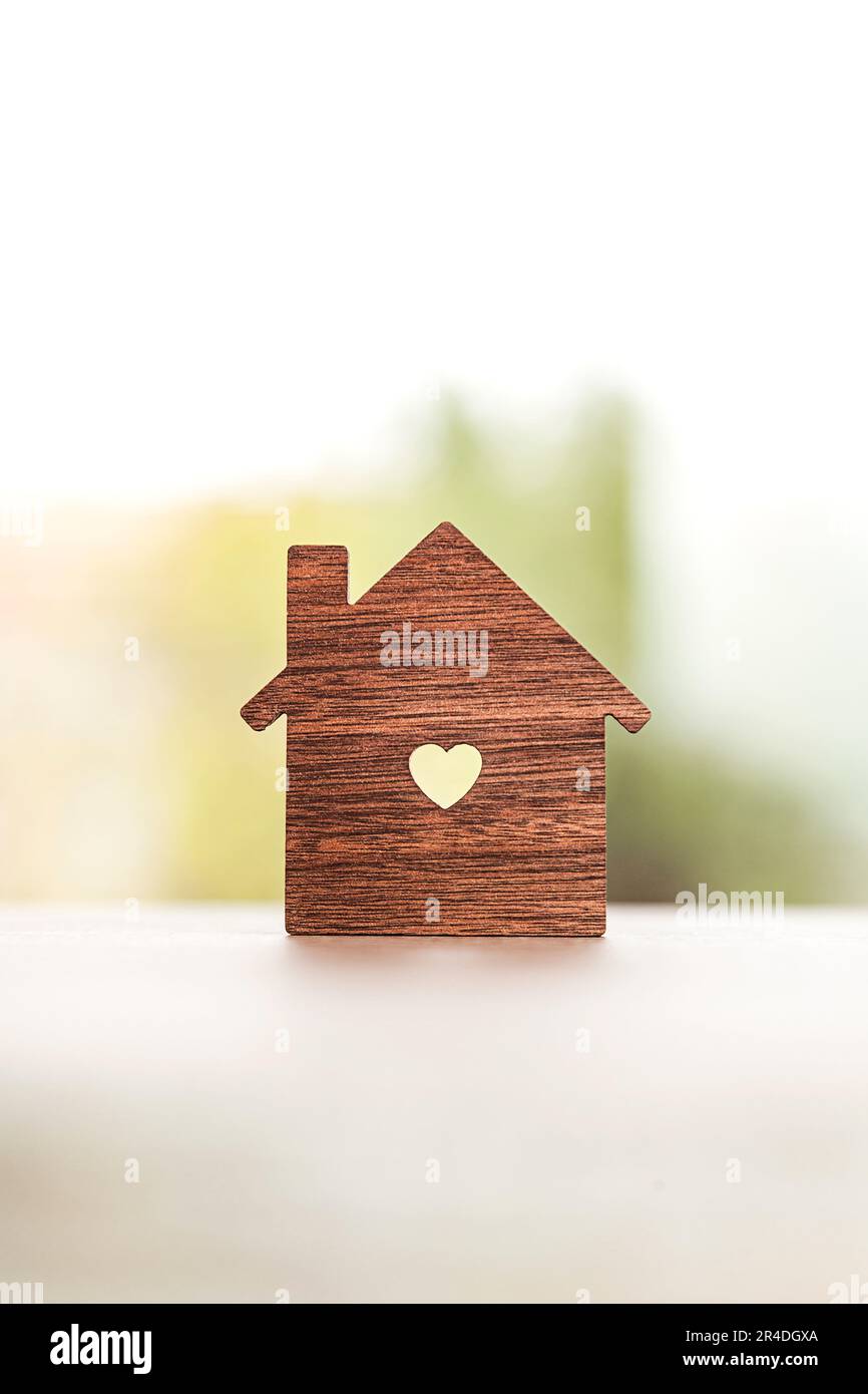 Gros plan d'une silhouette en forme de maison avec un trou en forme de coeur au centre d'une table avec une fenêtre en arrière-plan. Banque D'Images